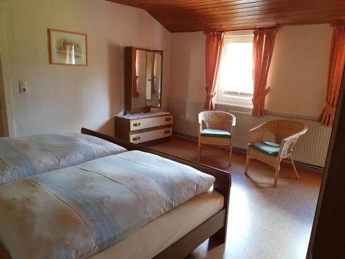 sypialnia z łóżkiem, 2 krzesłami i lustrem w obiekcie Haus Waldblick w mieście Hohegeiß