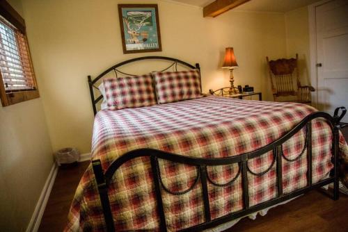 a bed with a checkered blanket in a bedroom at Prospect Cabin, Cozy 1-bedroom cabin with kitchen Dogs OK in Estes Park