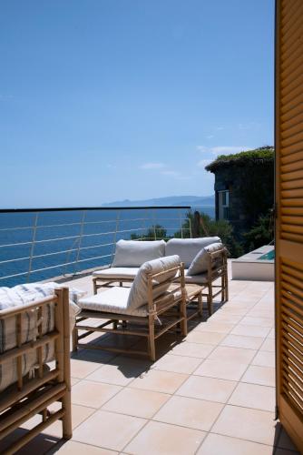 a row of lounge chairs on a balcony with the ocean at Villa Aiolos: above the sea, within Agios Nikolaos in Agios Nikolaos