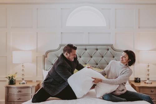 a man and woman sitting on a bed playing with a pillow at Queens Landing in Niagara on the Lake