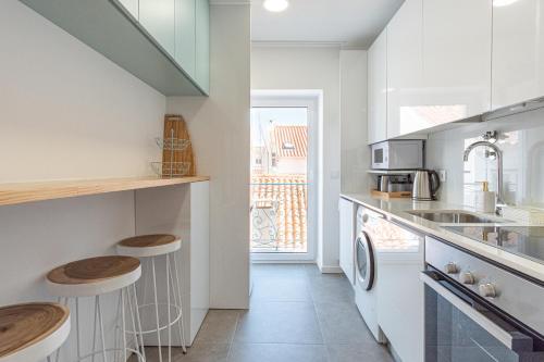 a kitchen with a sink and a counter with stools at Feel Nazaré - Saudade 57 in Nazaré