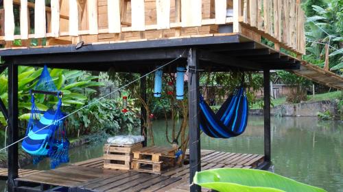 a house with a deck with hammocks on the water at Aventura Treehouse Glamping in Palmira