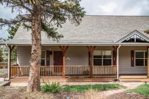 a house with a porch and a tree at Twin Owls Lodge, Great for families Master bedroom, Loft, full kitchen, Dogs OK in Estes Park