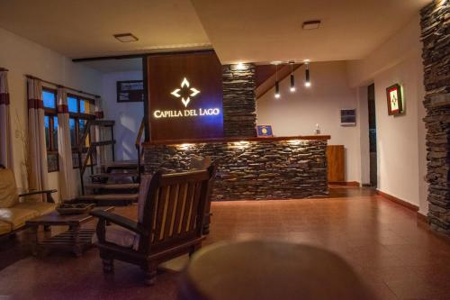 a lobby with chairs and a bar with a stone wall at Capilla del Lago in Villa Carlos Paz