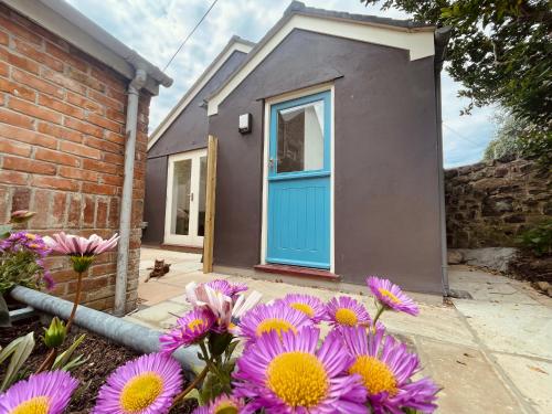 a house with a blue door and purple flowers at The Garden House in Penzance