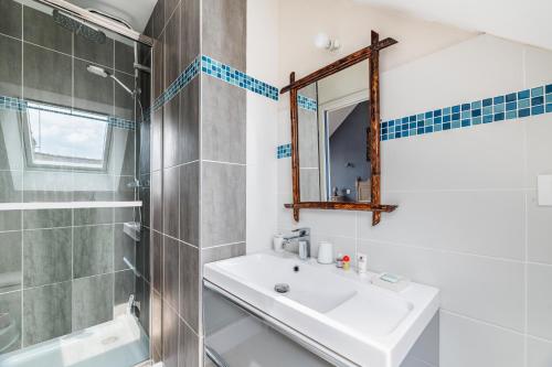 W łazience znajduje się umywalka, prysznic i lustro. w obiekcie La Maison des Fées w mieście Pleudihen-sur-Rance