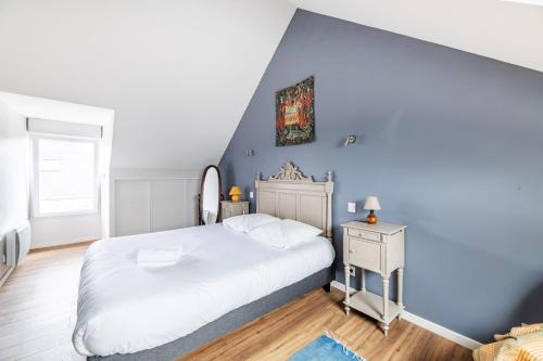 sypialnia z białym łóżkiem i niebieską ścianą w obiekcie La Maison des Fées w mieście Pleudihen-sur-Rance