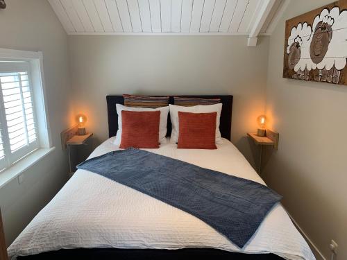 Un dormitorio con una cama con almohadas y dos lámparas. en Beach House Texel, en De Koog