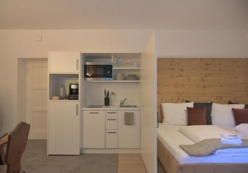 a white bedroom with a bed and a kitchen at CityChalet romantic Bozen in Bolzano