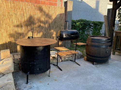 a table and a barrel and a grill and a table and bench at BELA VILA in Negotin