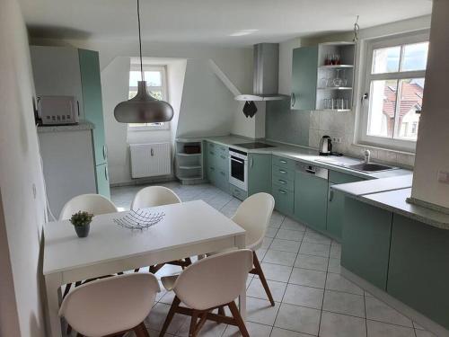 een keuken met groene kasten en een witte tafel en stoelen bij Gästewohnung Eulennest 