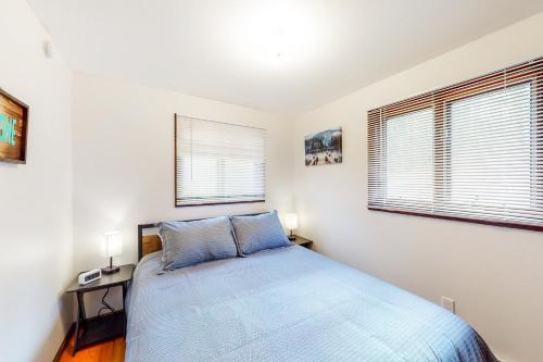 1 dormitorio con 1 cama azul y 2 ventanas en Lake House First Floor, en Vassalboro
