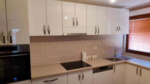 a kitchen with white cabinets and a sink and a window at ENSA Apartments in Dubrave Gornje