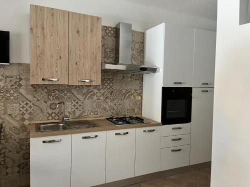 eine Küche mit weißen Schränken, einer Spüle und einem Herd in der Unterkunft A casa di Alessandra in Mailand