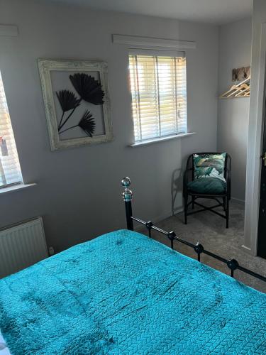 a bedroom with a blue bed and a chair at The Farrier's by Spires Accommodation A convenient place to stay for exploring Cannock Chase in Hednesford