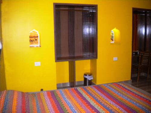 a yellow bedroom with a bed and a window at Ganpati Guest House in Varanasi