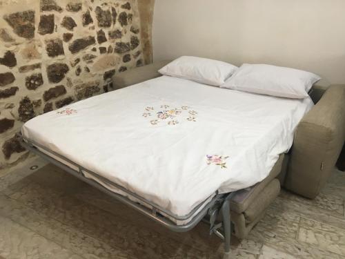 a bed with a white comforter with flowers on it at La Casetta in Altamura