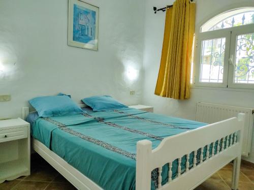 a bedroom with a bed with blue sheets and a window at The Shell Of The Beach in Hammamet