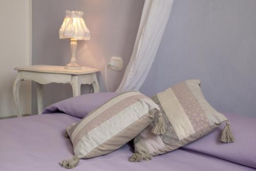 ein Bett mit zwei Kissen und einem Tisch mit einer Lampe in der Unterkunft Crealto in Alfiano Natta