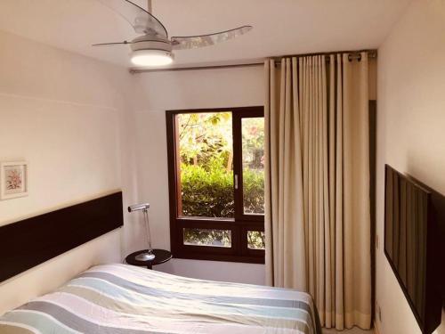 Schlafzimmer mit einem Bett und einem Fenster in der Unterkunft Apartamento 02 Porto Praia do Forte in Praia do Forte