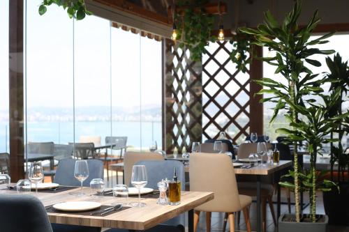 a restaurant with tables and chairs and windows at Aliko Hotel in Vlorë