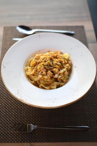 a white bowl of pasta with nuts on a table at Aliko Hotel in Vlorë