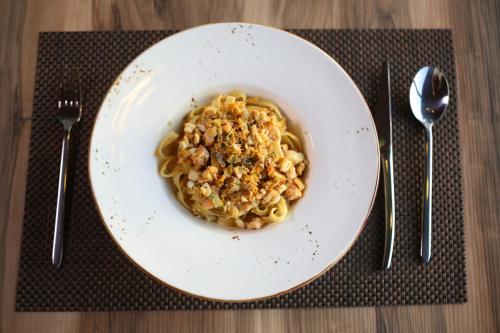 a plate of pasta with meat on a table with silverware at Aliko Hotel in Vlorë