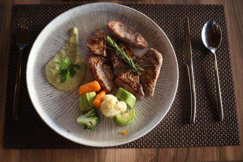 a plate of food with meat and vegetables on a table at Aliko Hotel in Vlorë