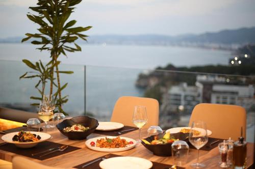 a table with plates of food and glasses of wine at Aliko Hotel in Vlorë