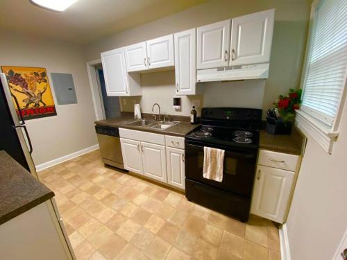 a kitchen with white cabinets and a black stove at Charming Condo Near Downtown, NCSU and PNC Arena in Raleigh