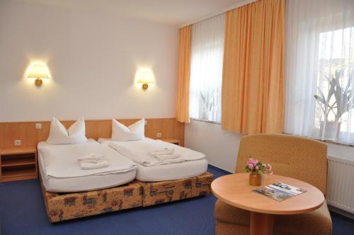 a hotel room with two beds and a table at Pension Lindenhof in Kromsdorf