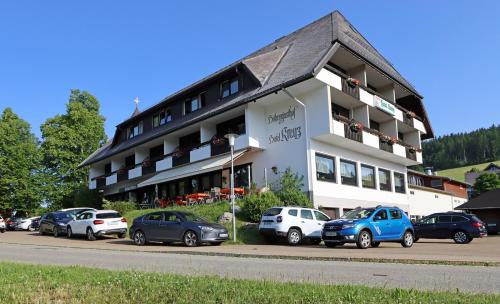 un grand bâtiment avec des voitures garées devant lui dans l'établissement Hotel Kreuz Höhengasthof, à Breitnau