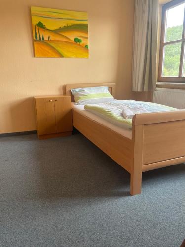 1 dormitorio con cama de madera y ventana en Pension Klosterhof, en Ebelsbach