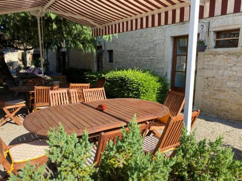 a wooden table and chairs under an umbrella at Maison Belles Pierres in Montagny-lès-Beaune