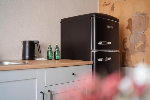 a black refrigerator in a kitchen with bottles on a counter at Apartaments Nr.33 (Viesu Nr.3) in Talsi