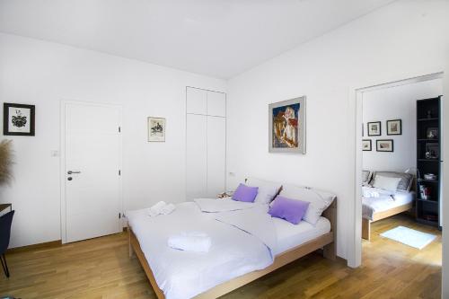 a white bedroom with a bed with purple pillows at F9 and New F9 in Zagreb