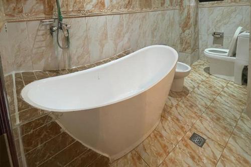 a bathroom with a bath tub and a toilet at Convivium Home Hotel in Douala