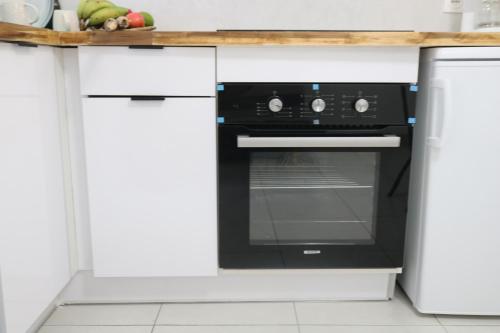 a black oven in a kitchen with white cabinets at Le Moringa in Baie-Mahault