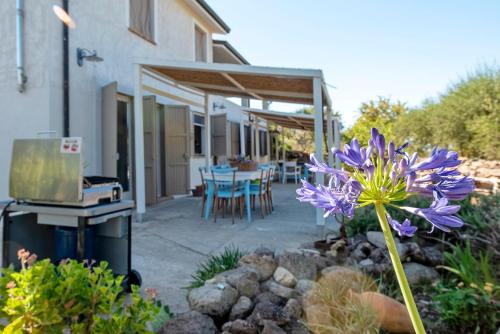 a patio with a table and a purple flower at Lu Casal de Fiò in Alghero