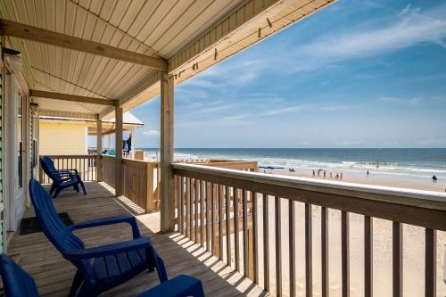 a porch with chairs and a view of the beach at Absolute Beach by Oak Island Accommodations in Oak Island