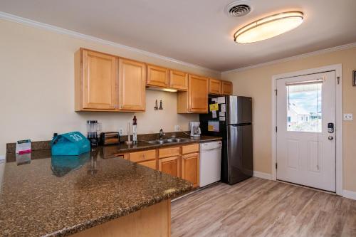 a kitchen with wooden cabinets and a black refrigerator at Absolute Beach by Oak Island Accommodations in Oak Island