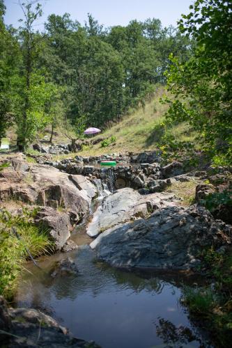 an umbrella on the rocks next to a river at Brvnara Mila Vila in Pranjani