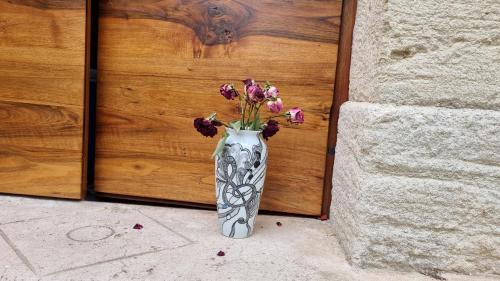 een vaas gevuld met bloemen voor een houten deur bij La maison des secrets in Bédoin