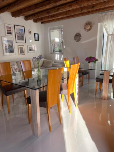 a dining room with a glass table and chairs at Onda Marina B&B Superior in Marano Lagunare