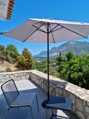 a patio with two chairs and an umbrella at Melissafarm Guest House in Ancient Epidauros