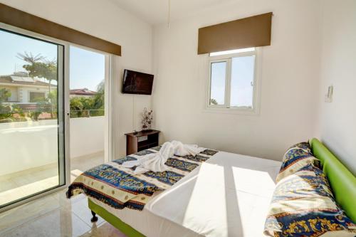 a white bedroom with a bed and a window at Villa Mario - 2min walk from Kapparis Beach in Paralimni
