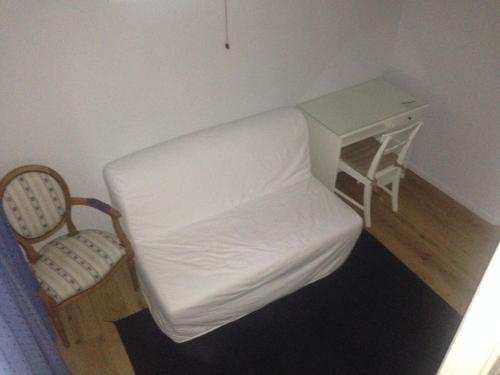 a small bedroom with a white bed and a chair at Gîte Du Haut Ballot in Wambrechies