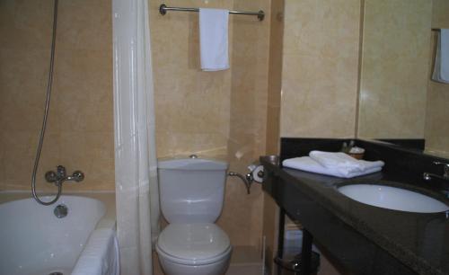 a bathroom with a toilet and a sink and a tub at Hotel Ancor in Bucharest