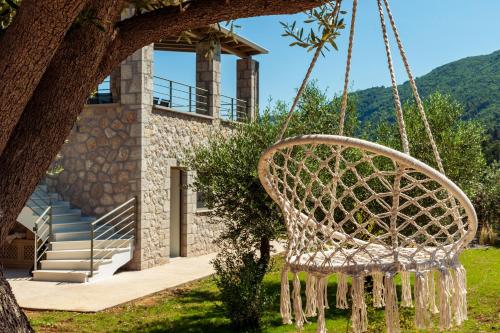 a swinging chair in front of a house at Mylos Mountain Villas- Villa Giorgio in Agios Nikitas
