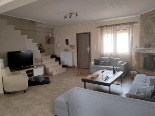 a living room with couches and a television and stairs at Nikos House Megara in Megara